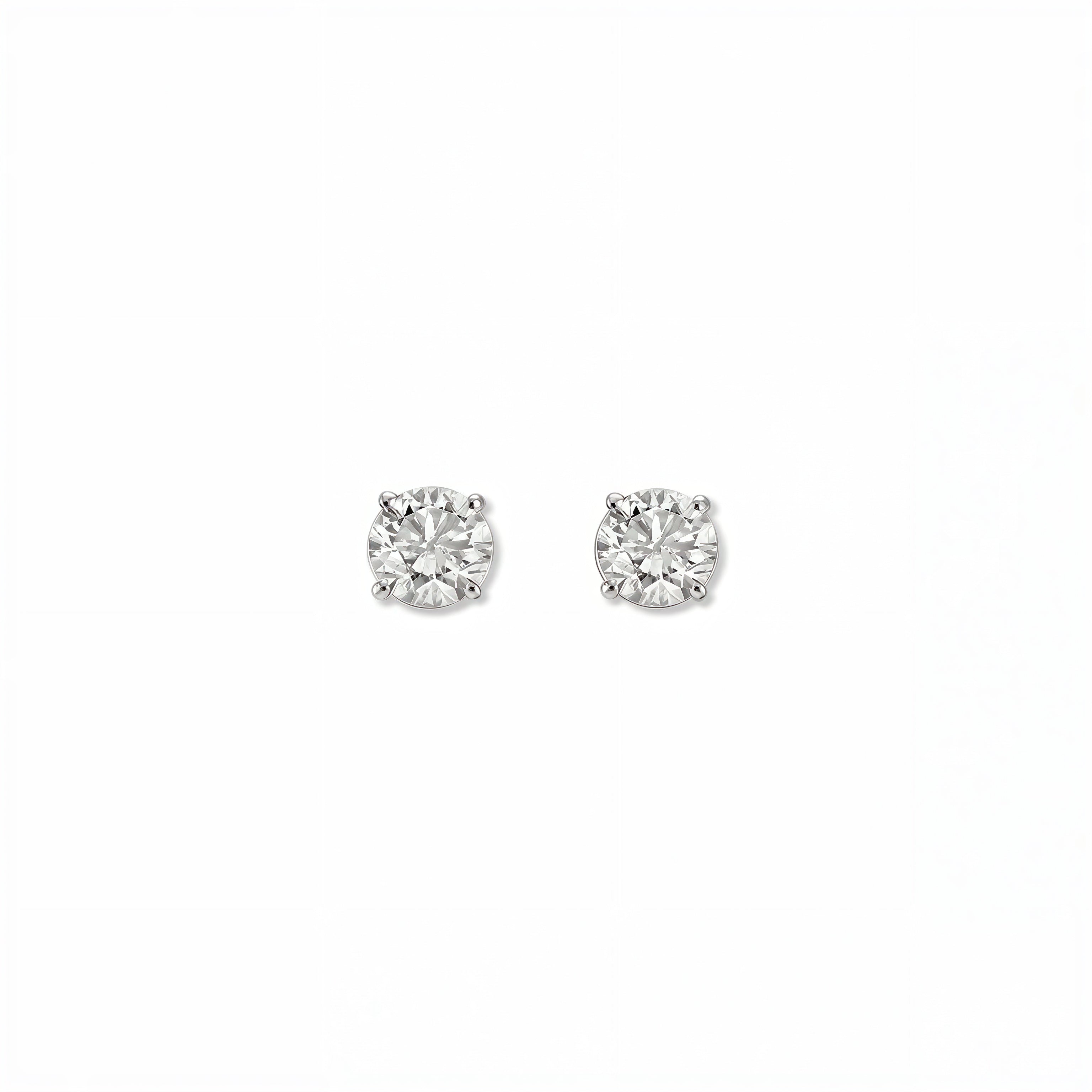 A pair of Round White Cubic Zirconia Stud Earrings 4mm by Skōsh Jewelry, featuring round, faceted clear stones in a four-prong sterling silver setting, displayed against a white background.