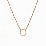 An Infinity Circle Necklace by Skōsh Jewelry, featuring a single open circle pendant attached at both sides to a delicate gold cable chain, displayed against a white background.