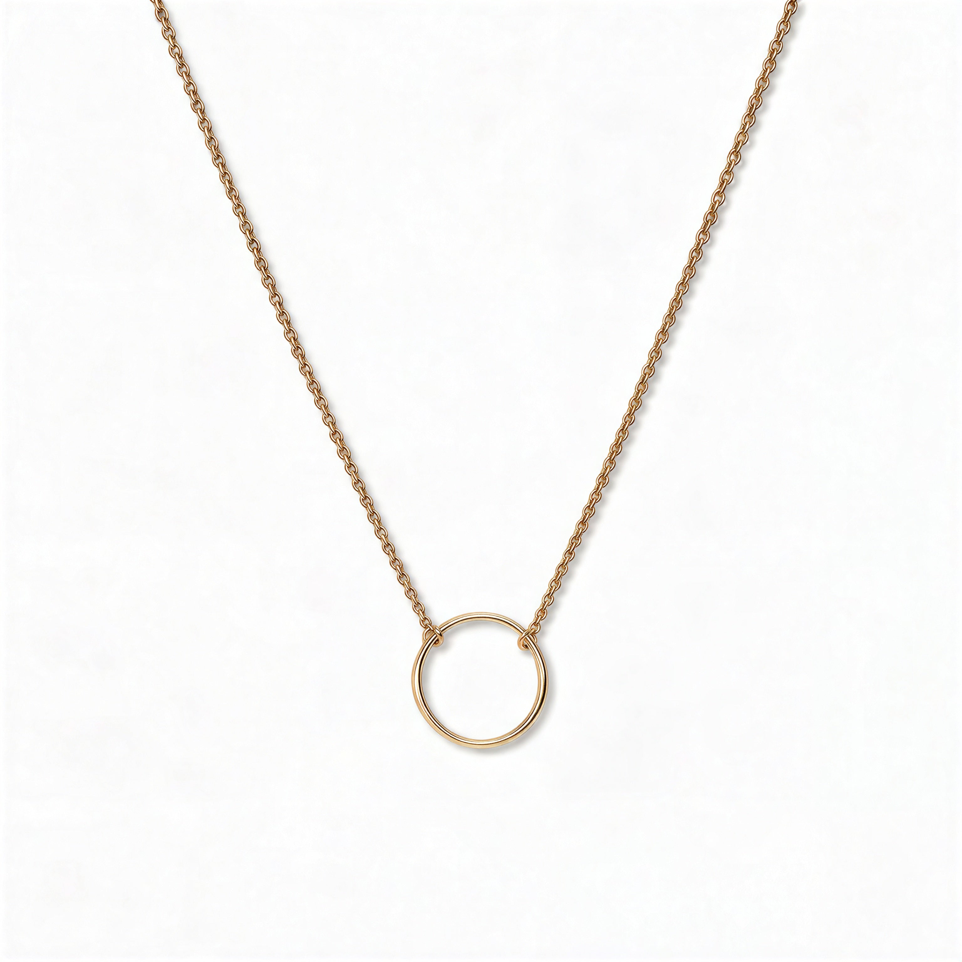 An Infinity Circle Necklace by Skōsh Jewelry, featuring a single open circle pendant attached at both sides to a delicate gold cable chain, displayed against a white background.