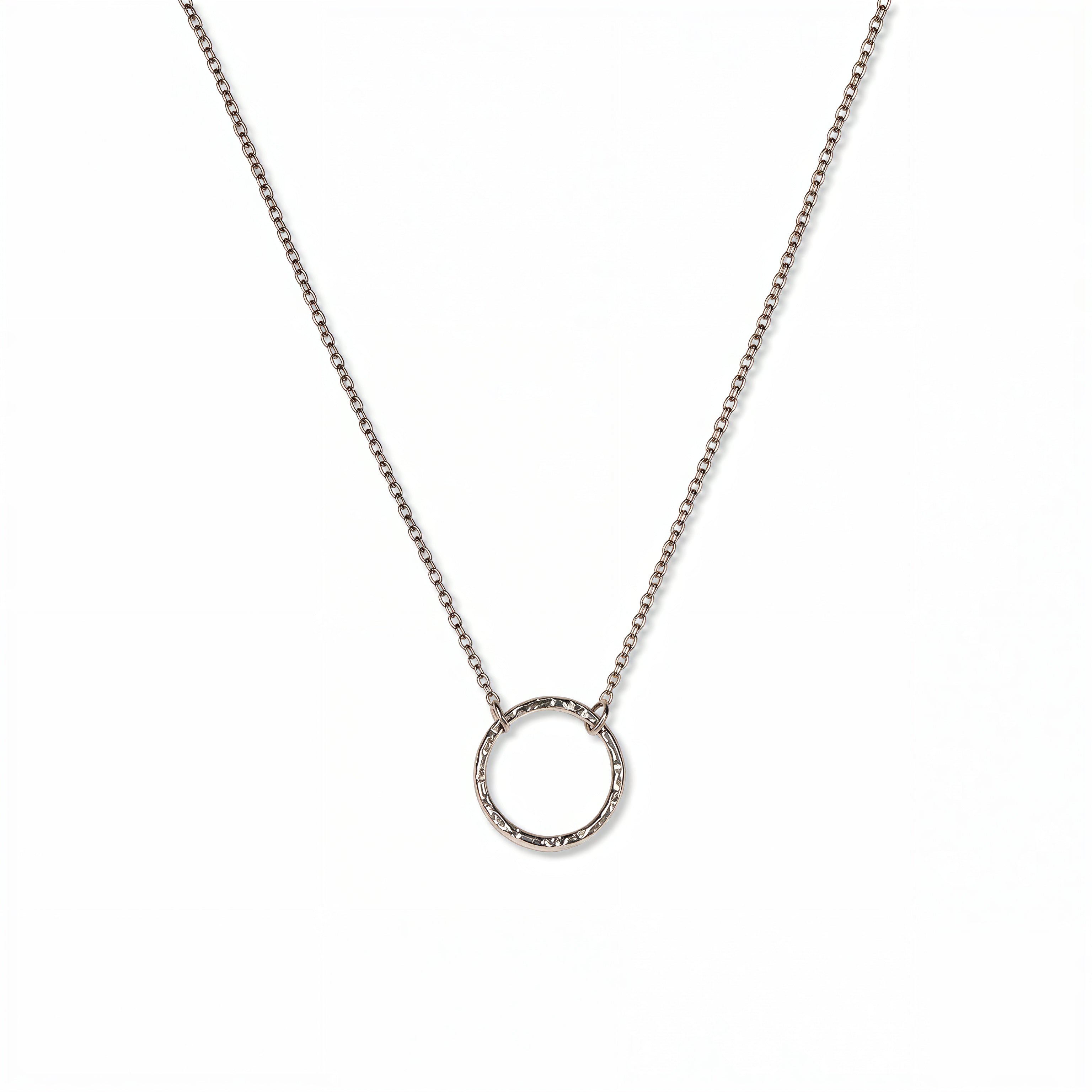 An Aura Hammered Circle Necklace by Skōsh Jewelry, featuring an open circle with a hammered, textured finish on a fine sterling silver chain, displayed against a white background.