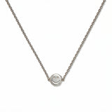 A Skōsh Kids Smiley Face Necklace by Skōsh Jewelry, featuring a small round smiley face charm set sideways on a fine sterling silver chain, displayed against a white background.