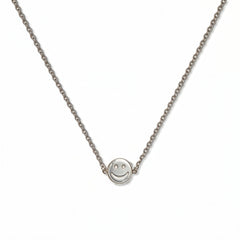 A Skōsh Kids Smiley Face Necklace by Skōsh Jewelry, featuring a small round smiley face charm set sideways on a fine sterling silver chain, displayed against a white background.