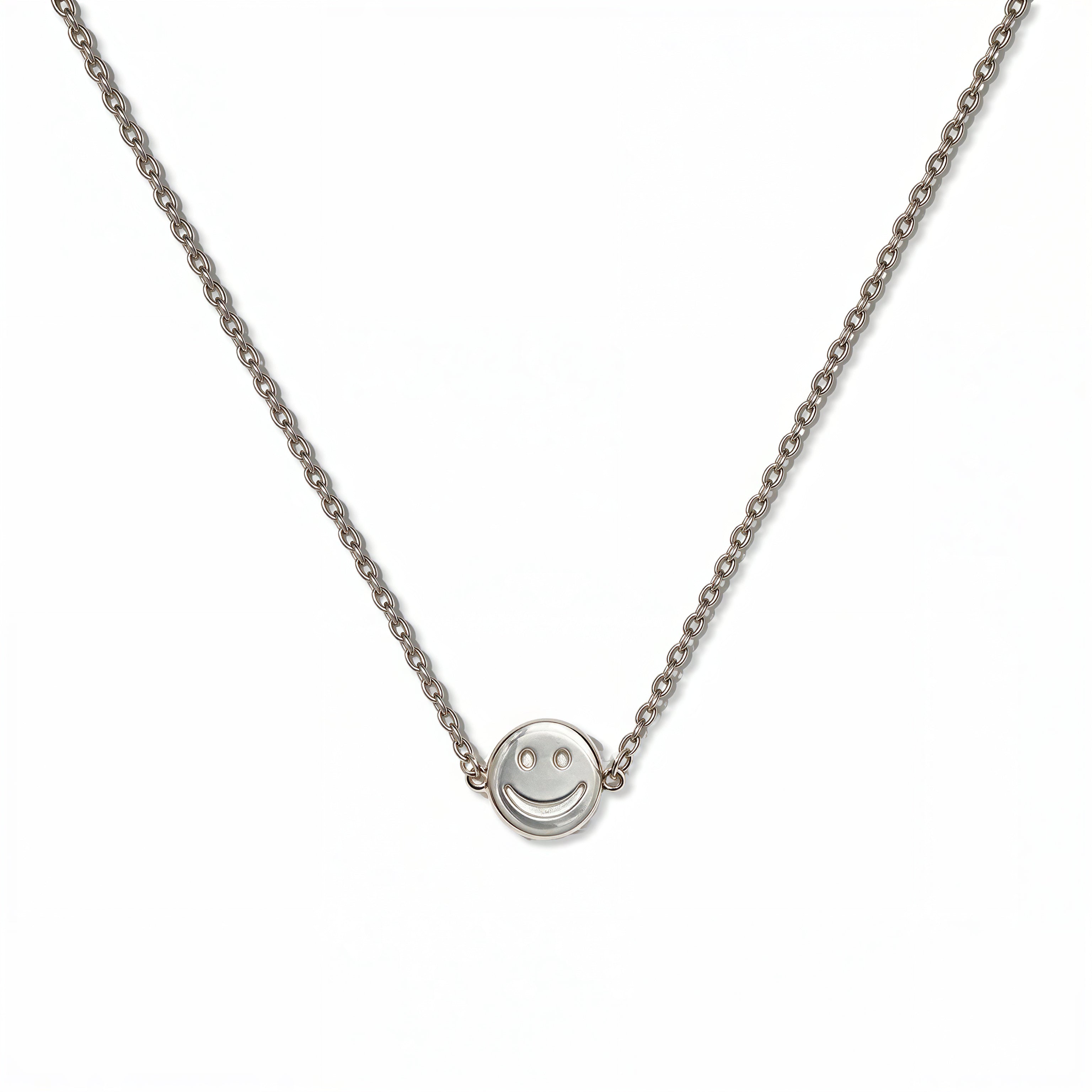 A Skōsh Kids Smiley Face Necklace by Skōsh Jewelry, featuring a small round smiley face charm set sideways on a fine sterling silver chain, displayed against a white background.