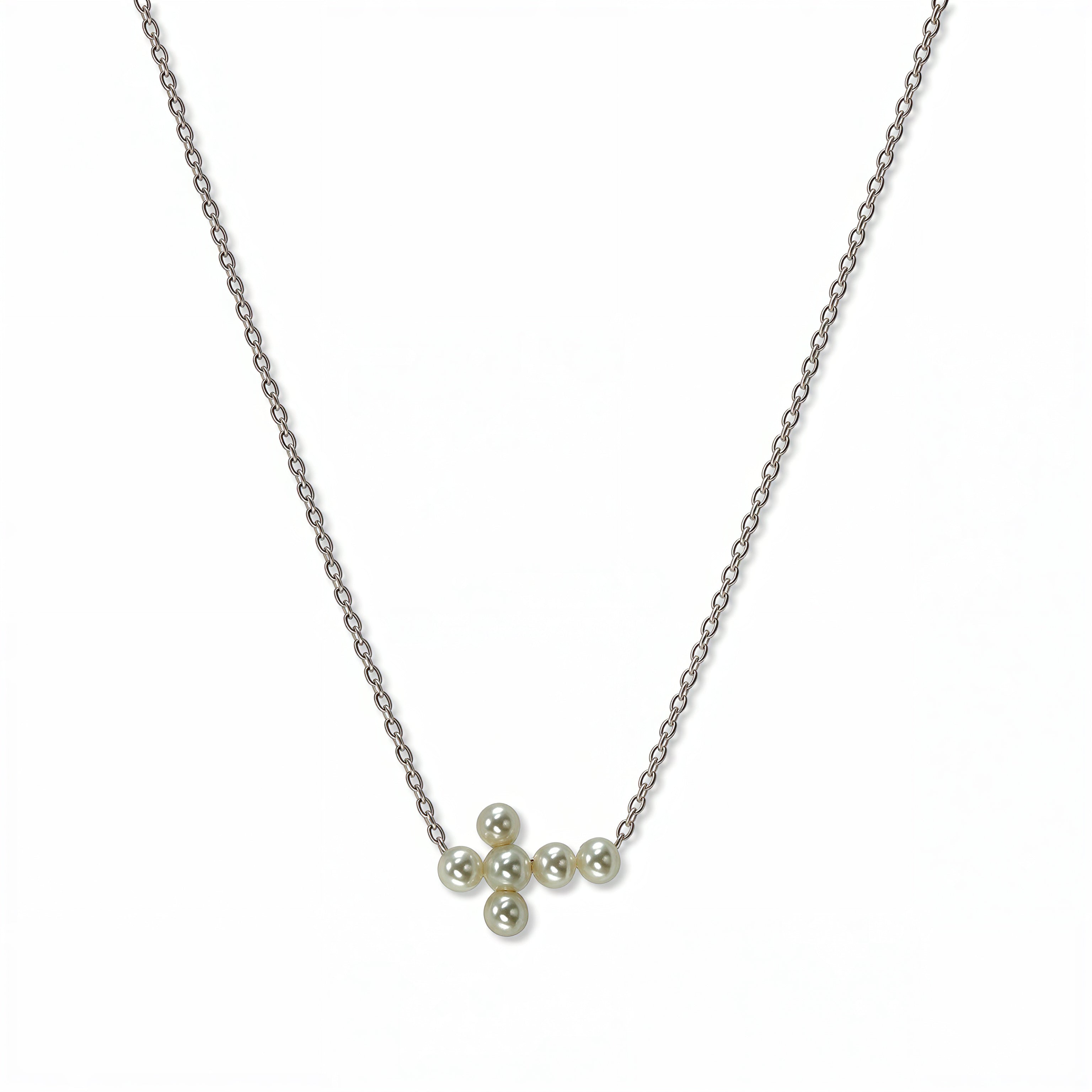 A Skōsh Kids Freshwater Pearl Sideways Cross Necklace by Skōsh Jewelry, featuring a tiny sideways cross made of small white pearls on a fine sterling silver chain, displayed against a white background.