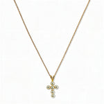 A Skōsh Kids Freshwater Pearl Cross Pendant Necklace by Skōsh Jewelry, featuring a small cross pendant made of tiny white pearl beads hanging from a fine gold chain, displayed against a white background.