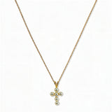 A Skōsh Kids Freshwater Pearl Cross Pendant Necklace by Skōsh Jewelry, featuring a small cross pendant made of tiny white pearl beads hanging from a fine gold chain, displayed against a white background.