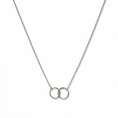 A Skōsh Kids Interlocking Circles Friendship Necklace by Skōsh Jewelry, featuring two small interlocking circles on a fine sterling silver chain, displayed against a white background.