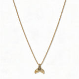 A Skōsh Kids Mermaid Tail Pendant Necklace by Skōsh Jewelry, featuring a small textured mermaid tail pendant on a fine gold chain, displayed against a white background.