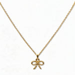 A Skōsh Kids Ribbon Bow Pendant Necklace by Skōsh Jewelry, featuring a dainty ribbon bow pendant on a fine gold chain, displayed against a white background.
