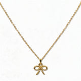 A Skōsh Kids Ribbon Bow Pendant Necklace by Skōsh Jewelry, featuring a dainty ribbon bow pendant on a fine gold chain, displayed against a white background.