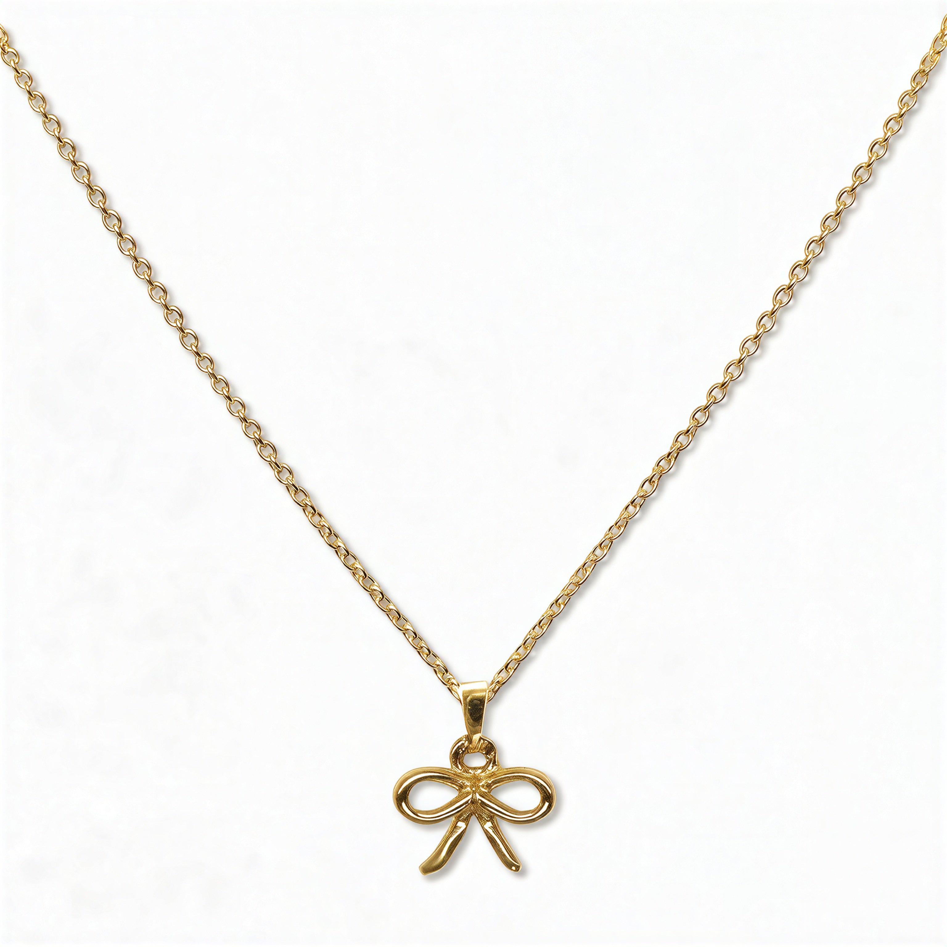A Skōsh Kids Ribbon Bow Pendant Necklace by Skōsh Jewelry, featuring a dainty ribbon bow pendant on a fine gold chain, displayed against a white background.