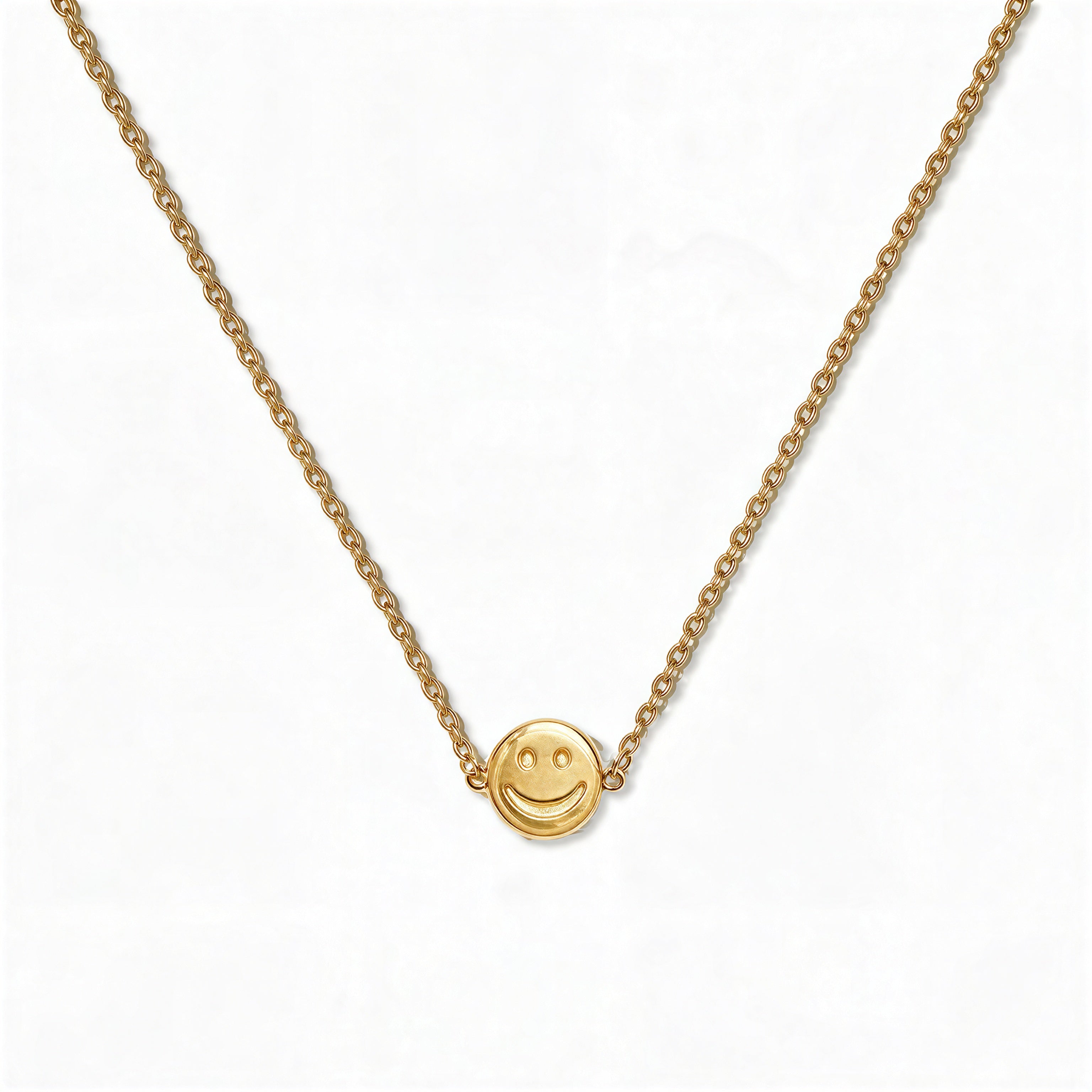 A Skōsh Kids Smiley Face Necklace by Skōsh Jewelry, featuring a small round smiley face charm set sideways on a fine gold chain, displayed against a white background.