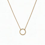 An Aura Hammered Circle Necklace by Skōsh Jewelry, featuring an open circle with a hammered, textured finish on a fine gold chain, displayed against a white background.