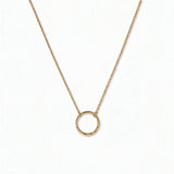 An Aura Hammered Circle Necklace by Skōsh Jewelry, featuring an open circle with a hammered, textured finish on a fine gold chain, displayed against a white background.