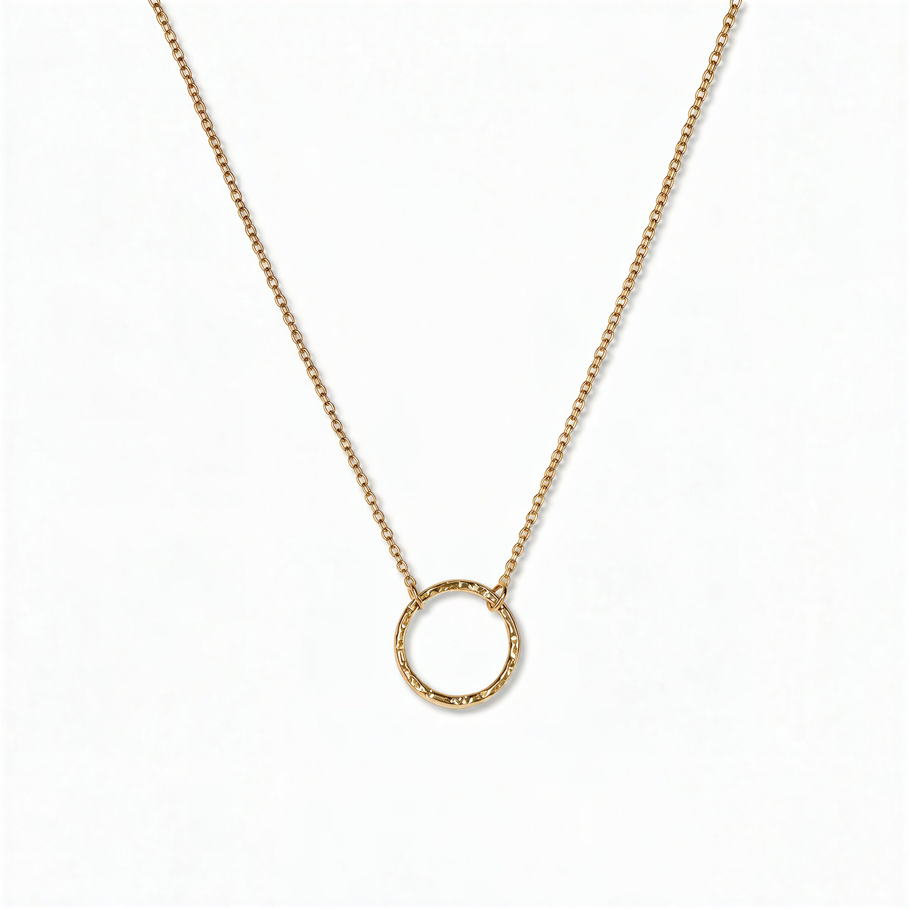 An Aura Hammered Circle Necklace by Skōsh Jewelry, featuring an open circle with a hammered, textured finish on a fine gold chain, displayed against a white background.