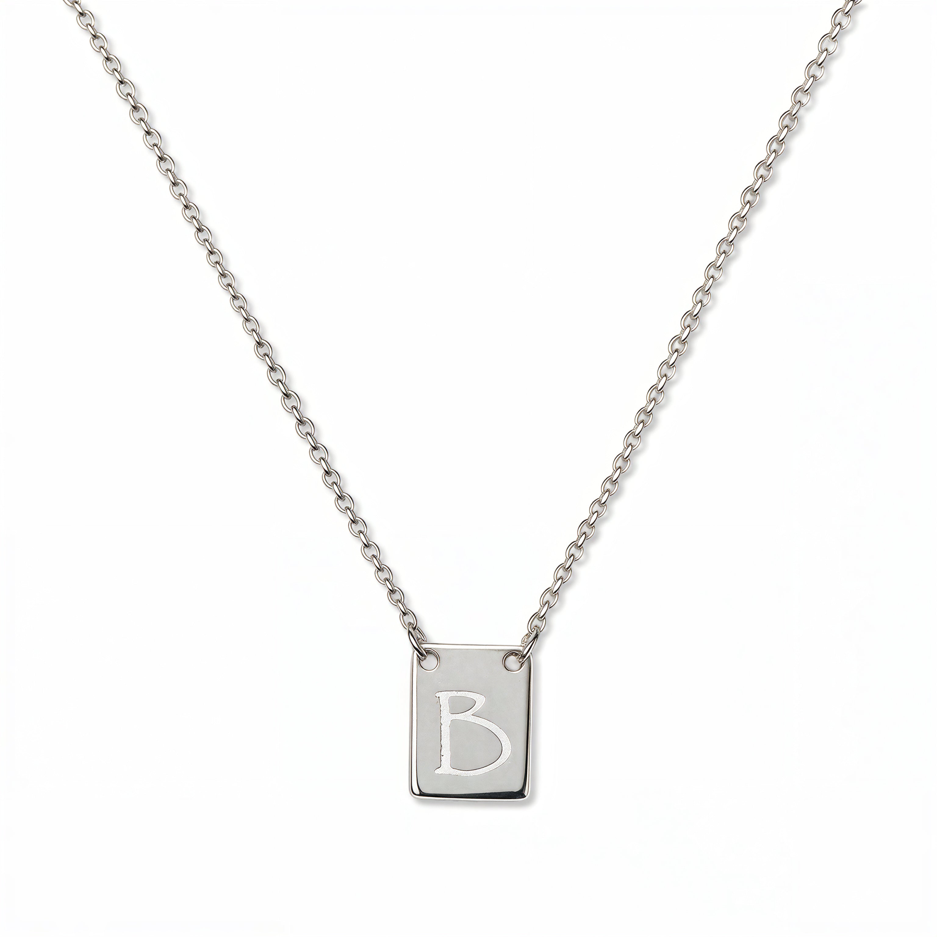 An Engraved Initial Necklace Letter B by Skōsh Jewelry, featuring a small rectangular tag engraved with the letter B on a fine sterling silver chain, displayed against a white background.