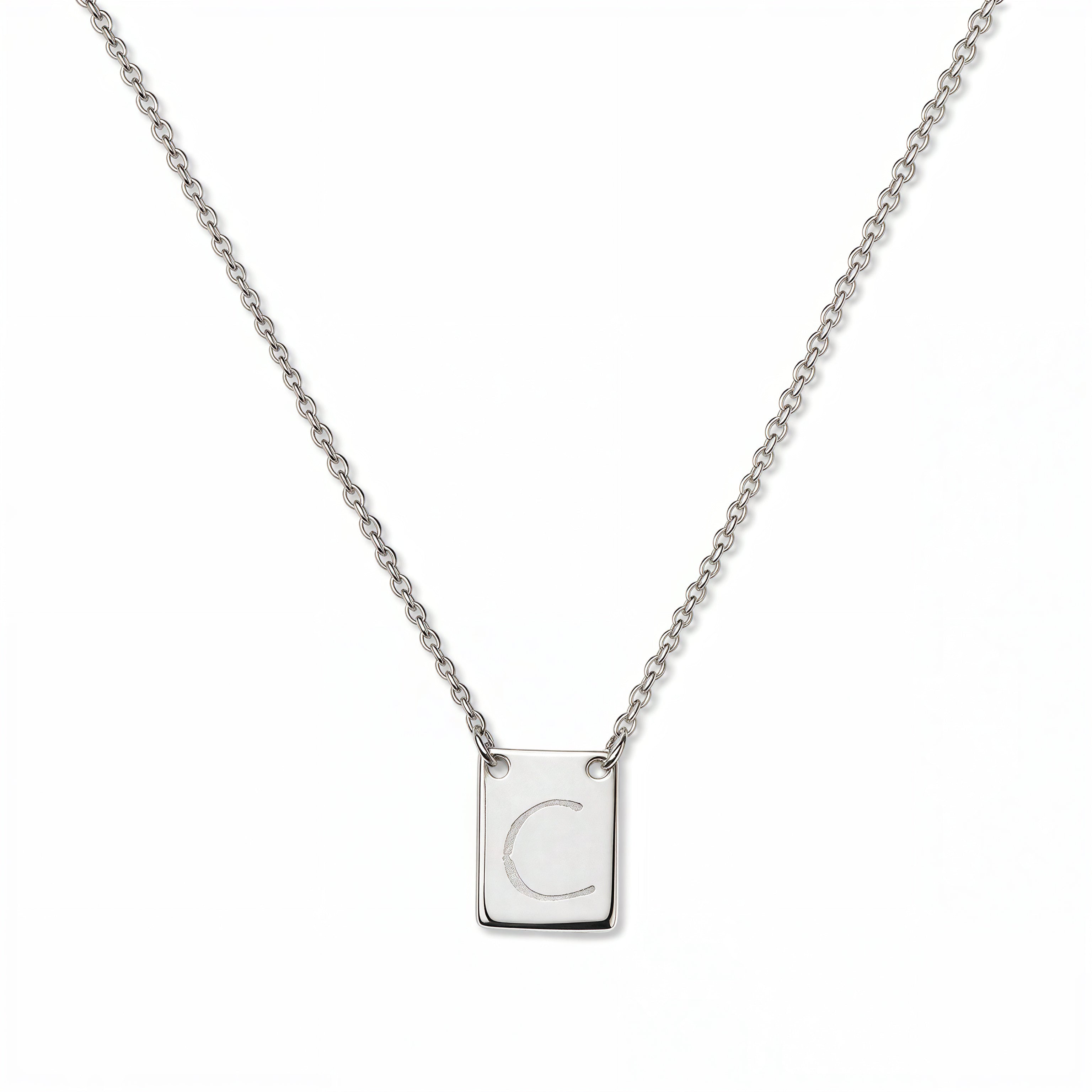An Engraved Initial Necklace Letter C by Skōsh Jewelry, featuring a small rectangular tag engraved with the letter C on a fine sterling silver chain, displayed against a white background.