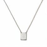 An Engraved Initial Necklace Letter D by Skōsh Jewelry, featuring a small rectangular tag engraved with the letter D on a fine sterling silver chain, displayed against a white background.