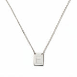 An Engraved Initial Necklace Letter E by Skōsh Jewelry, featuring a small rectangular tag engraved with the letter E on a fine sterling silver chain, displayed against a white background.