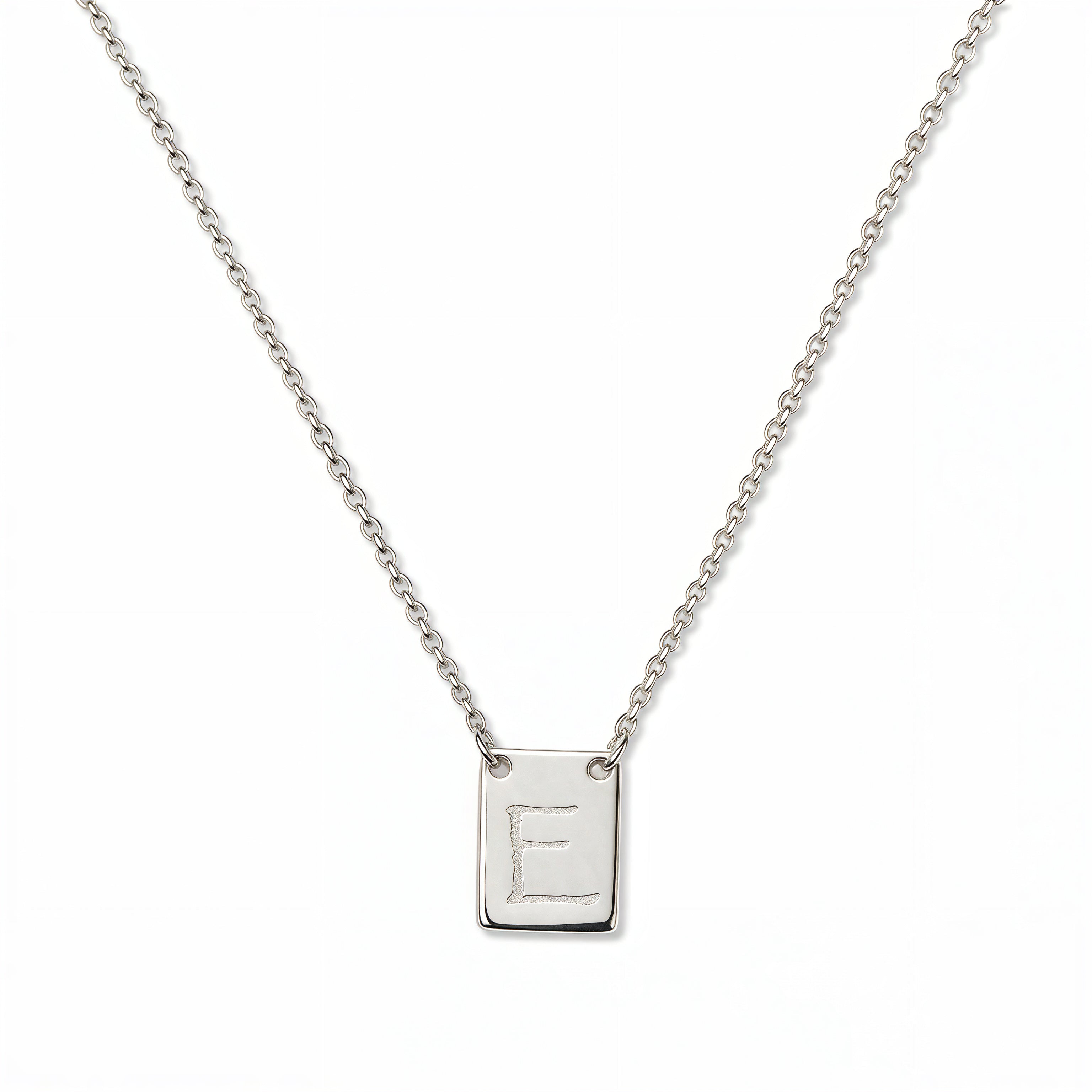 An Engraved Initial Necklace Letter E by Skōsh Jewelry, featuring a small rectangular tag engraved with the letter E on a fine sterling silver chain, displayed against a white background.