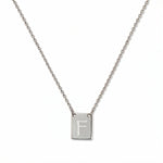 An Engraved Initial Necklace Letter F by Skōsh Jewelry, featuring a small rectangular tag engraved with the letter F on a fine sterling silver chain, displayed against a white background.