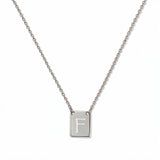 An Engraved Initial Necklace Letter F by Skōsh Jewelry, featuring a small rectangular tag engraved with the letter F on a fine sterling silver chain, displayed against a white background.