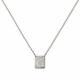 An Engraved Initial Necklace Letter G by Skōsh Jewelry, featuring a small rectangular tag engraved with the letter G on a fine sterling silver chain, displayed against a white background.