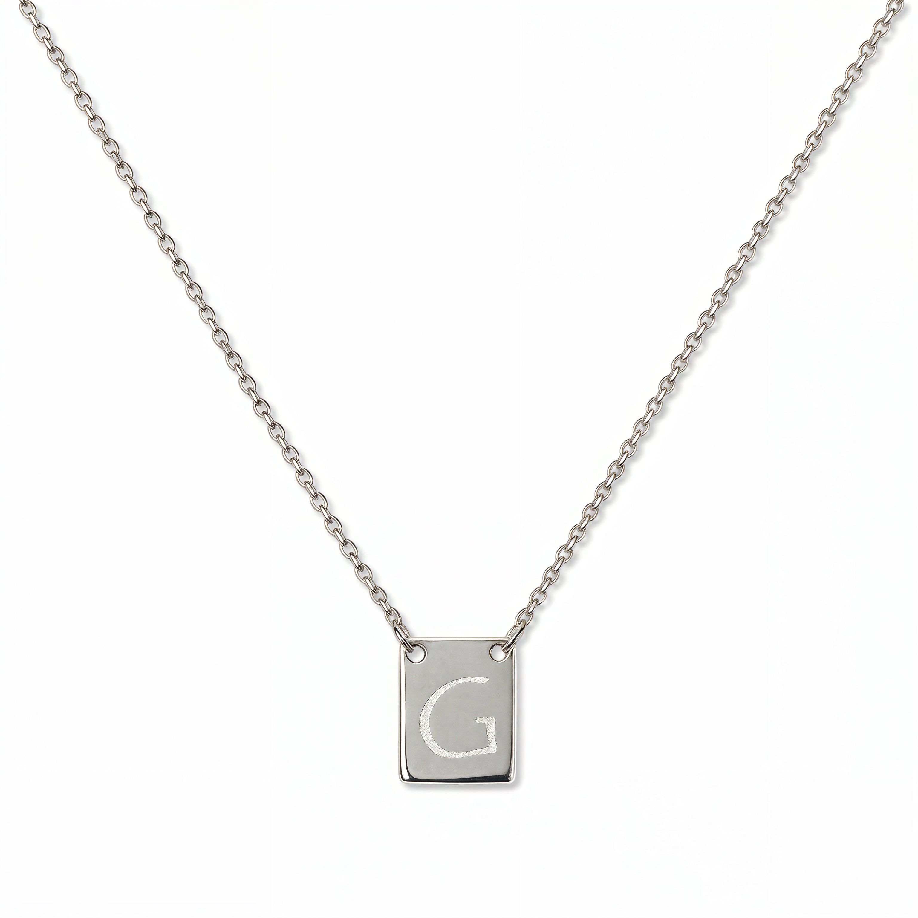 An Engraved Initial Necklace Letter G by Skōsh Jewelry, featuring a small rectangular tag engraved with the letter G on a fine sterling silver chain, displayed against a white background.