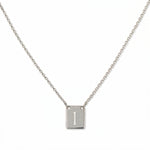 An Engraved Initial Necklace Letter I by Skōsh Jewelry, featuring a small rectangular tag engraved with the letter I on a fine sterling silver chain, displayed against a white background.