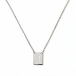 An Engraved Initial Necklace Letter J by Skōsh Jewelry, featuring a small rectangular tag engraved with the letter J on a fine sterling silver chain, displayed against a white background.
