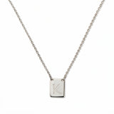 An Engraved Initial Necklace Letter K by Skōsh Jewelry, featuring a small rectangular tag engraved with the letter K on a fine sterling silver chain, displayed against a white background.