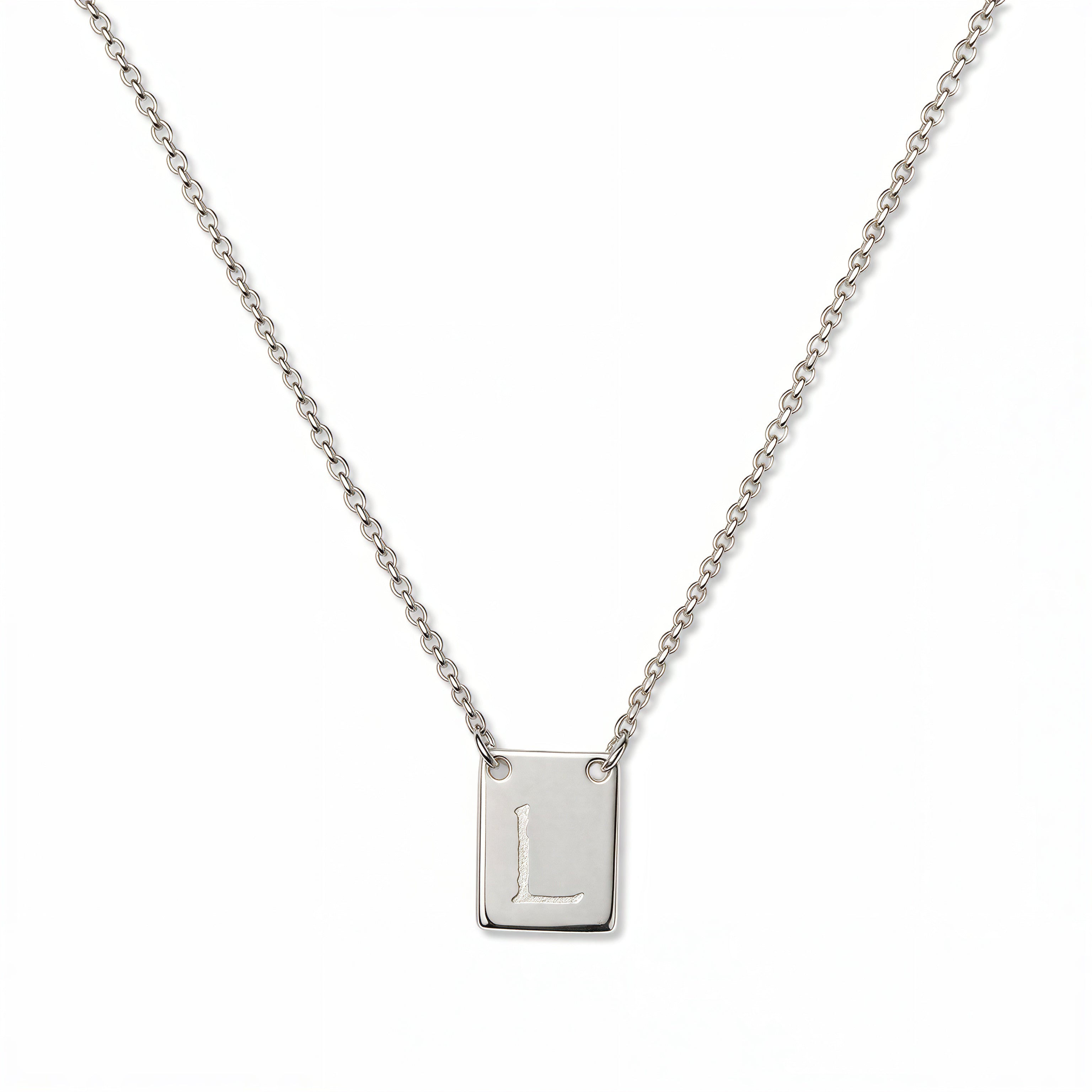 An Engraved Initial Necklace Letter L by Skōsh Jewelry, featuring a small rectangular tag engraved with the letter L on a fine sterling silver chain, displayed against a white background.