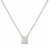 An Engraved Initial Necklace Letter M by Skōsh Jewelry, featuring a small rectangular tag engraved with the letter M on a fine sterling silver chain, displayed against a white background.