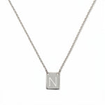 An Engraved Initial Necklace Letter N by Skōsh Jewelry, featuring a small rectangular tag engraved with the letter N on a fine sterling silver chain, displayed against a white background.