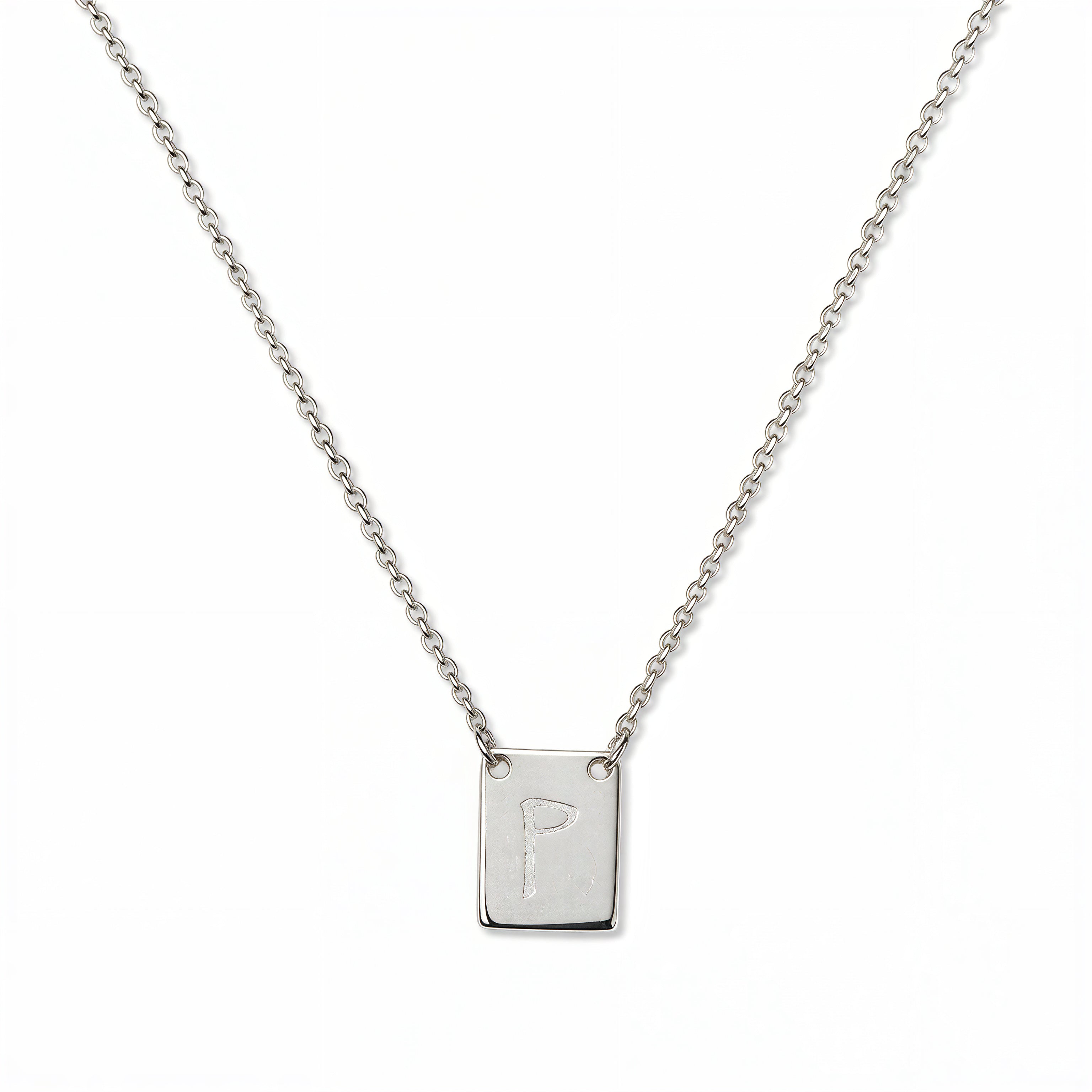 An Engraved Initial Necklace Letter P by Skōsh Jewelry, featuring a small rectangular tag engraved with the letter P on a fine sterling silver chain, displayed against a white background.