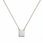 An Engraved Initial Necklace Letter R by Skōsh Jewelry, featuring a small rectangular tag engraved with the letter R on a fine sterling silver chain, displayed against a white background.