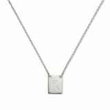 An Engraved Initial Necklace Letter R by Skōsh Jewelry, featuring a small rectangular tag engraved with the letter R on a fine sterling silver chain, displayed against a white background.