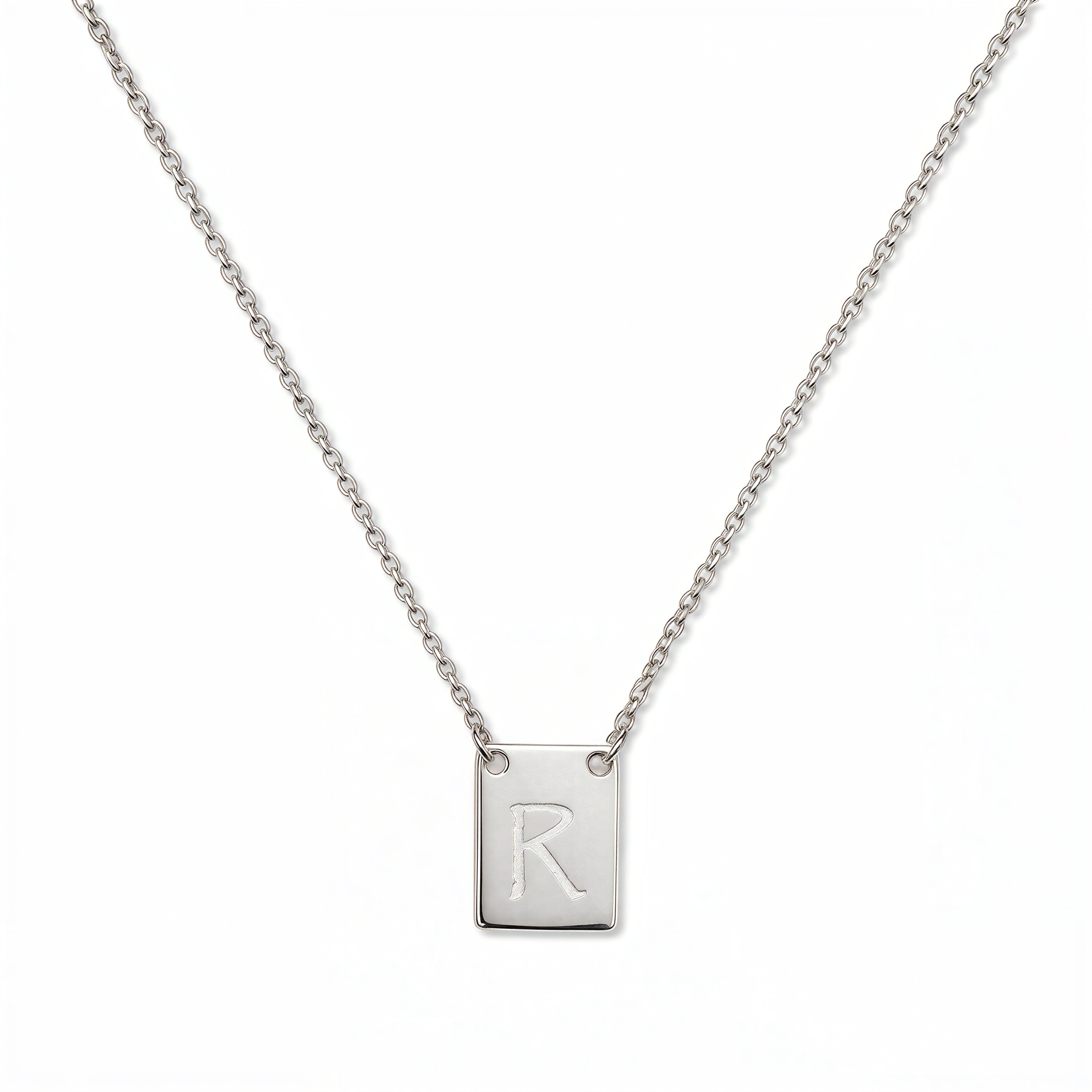 An Engraved Initial Necklace Letter R by Skōsh Jewelry, featuring a small rectangular tag engraved with the letter R on a fine sterling silver chain, displayed against a white background.