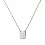 An Engraved Initial Necklace Letter S by Skōsh Jewelry, featuring a small rectangular tag engraved with the letter S on a fine sterling silver chain, displayed against a white background.