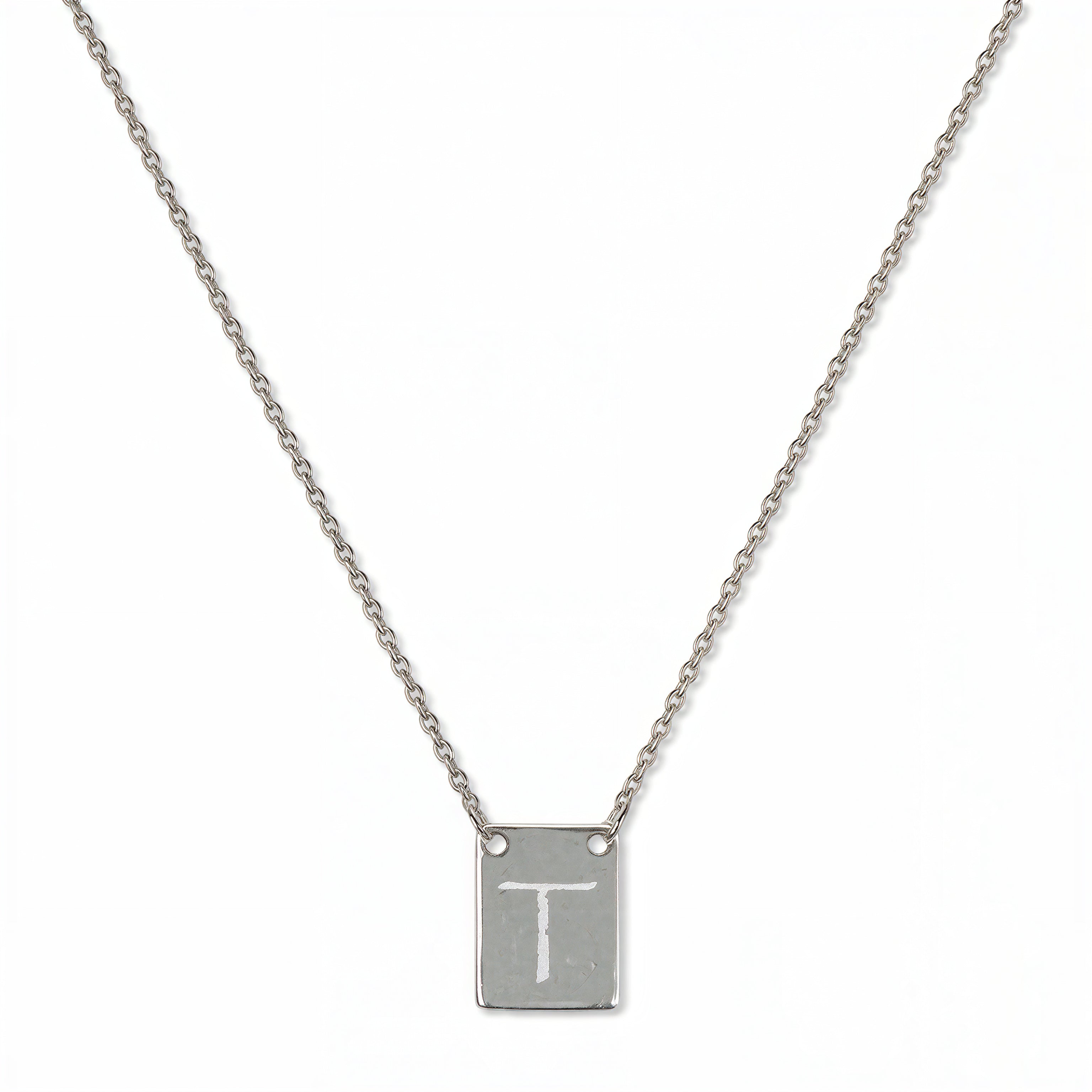 An Engraved Initial Necklace Letter T by Skōsh Jewelry, featuring a small rectangular tag engraved with the letter T on a fine sterling silver chain, displayed against a white background.