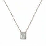 An Engraved Initial Necklace Letter U by Skōsh Jewelry, featuring a small rectangular tag engraved with the letter U on a fine sterling silver chain, displayed against a white background.