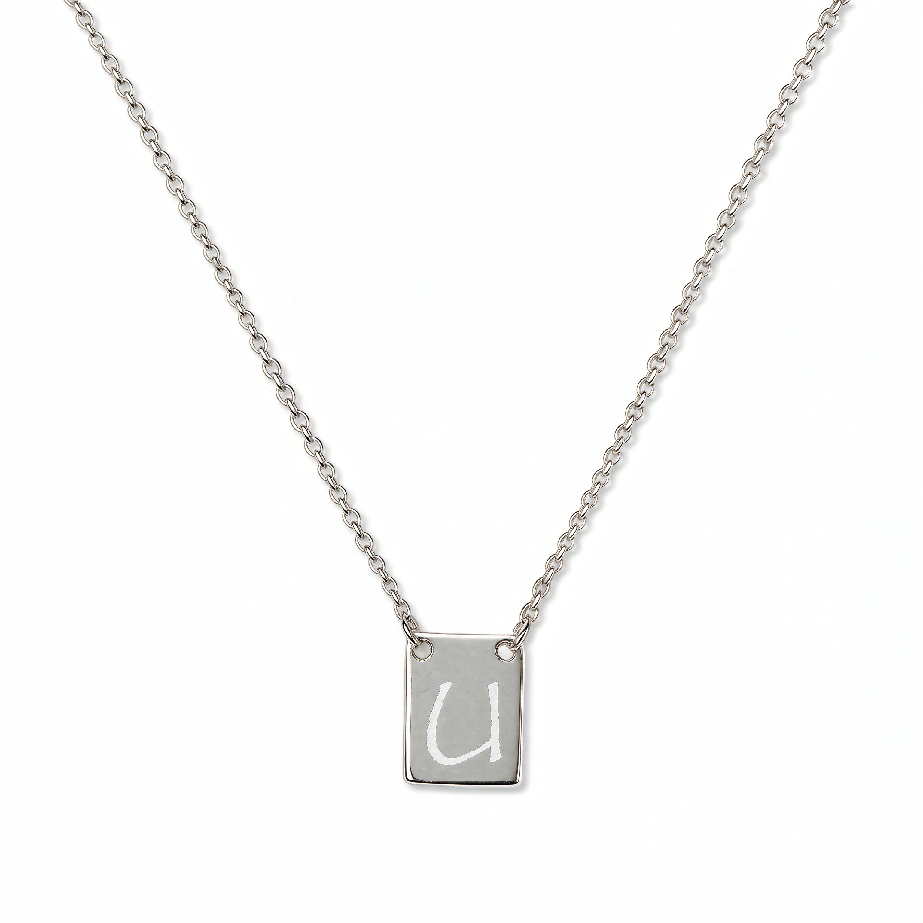 An Engraved Initial Necklace Letter U by Skōsh Jewelry, featuring a small rectangular tag engraved with the letter U on a fine sterling silver chain, displayed against a white background.