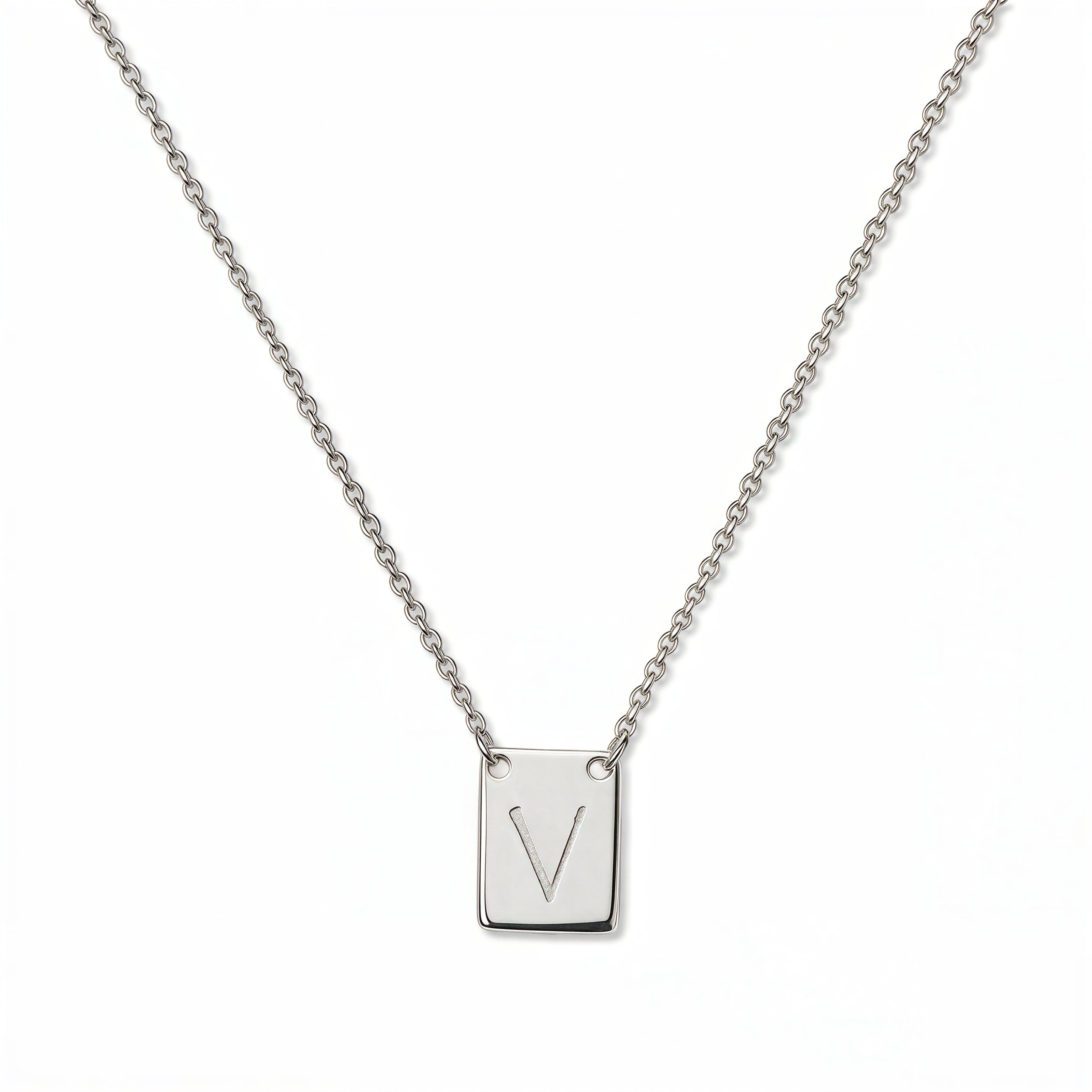 An Engraved Initial Necklace Letter V by Skōsh Jewelry, featuring a small rectangular tag engraved with the letter V on a fine sterling silver chain, displayed against a white background.