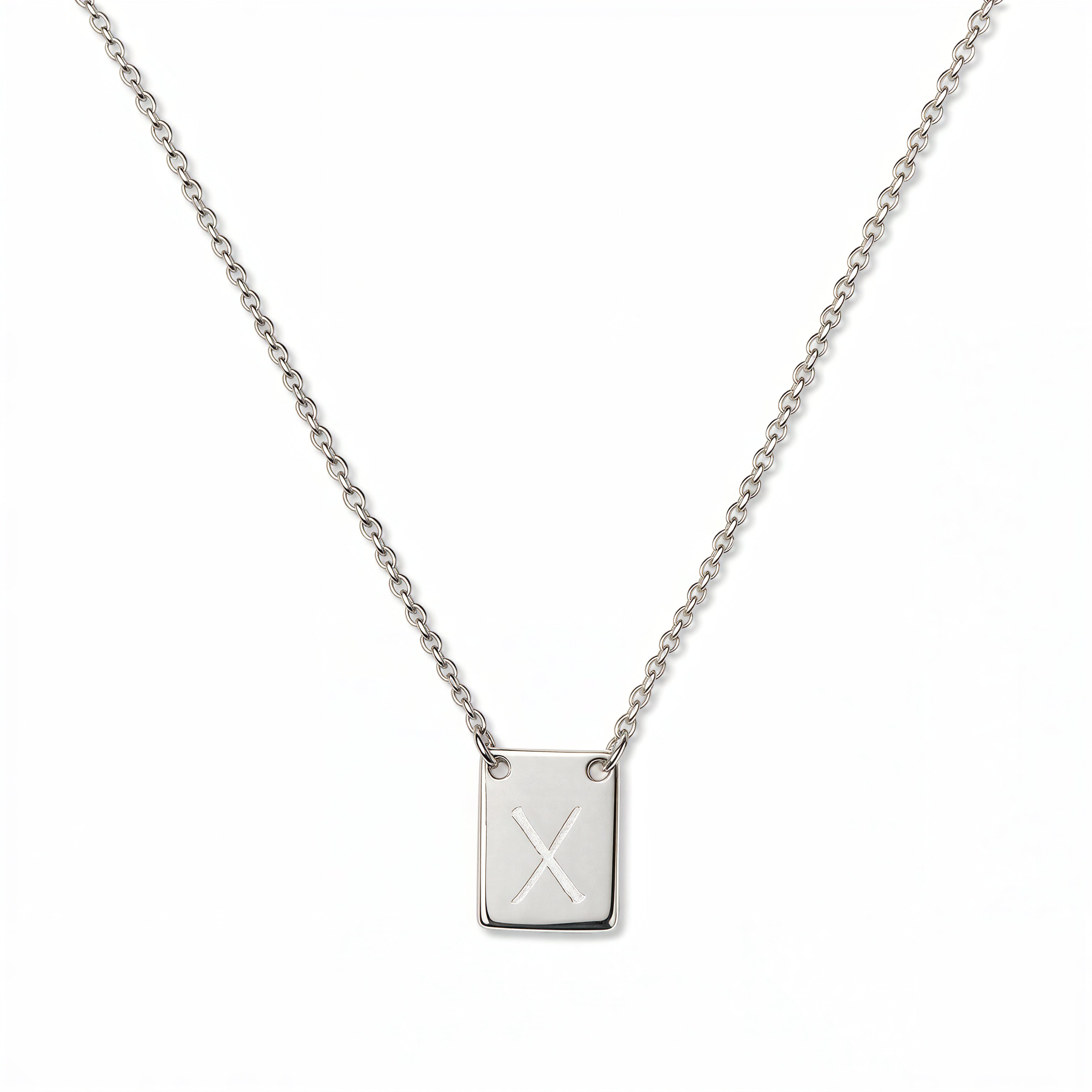 An Engraved Initial Necklace Letter X by Skōsh Jewelry, featuring a small rectangular tag engraved with the letter X on a fine sterling silver chain, displayed against a white background.