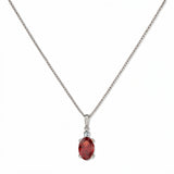A Skōsh Kids January Birthstone Oval Garnet Cubic Zirconia Necklace by Skōsh Jewelry, featuring an oval faceted deep red stone in a prong setting on a fine sterling silver chain, displayed against a white background.