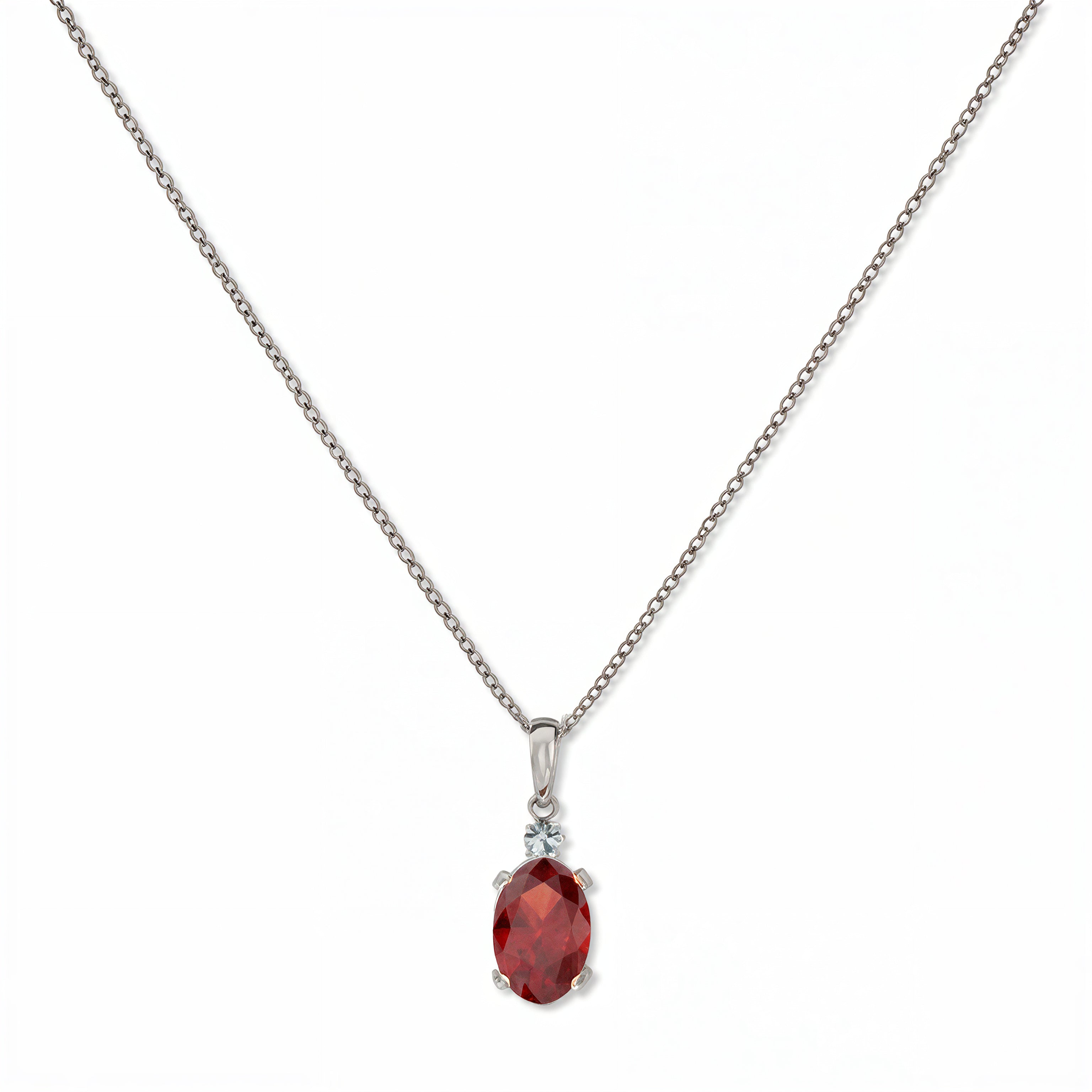 A Skōsh Kids January Birthstone Oval Garnet Cubic Zirconia Necklace by Skōsh Jewelry, featuring an oval faceted deep red stone in a prong setting on a fine sterling silver chain, displayed against a white background.