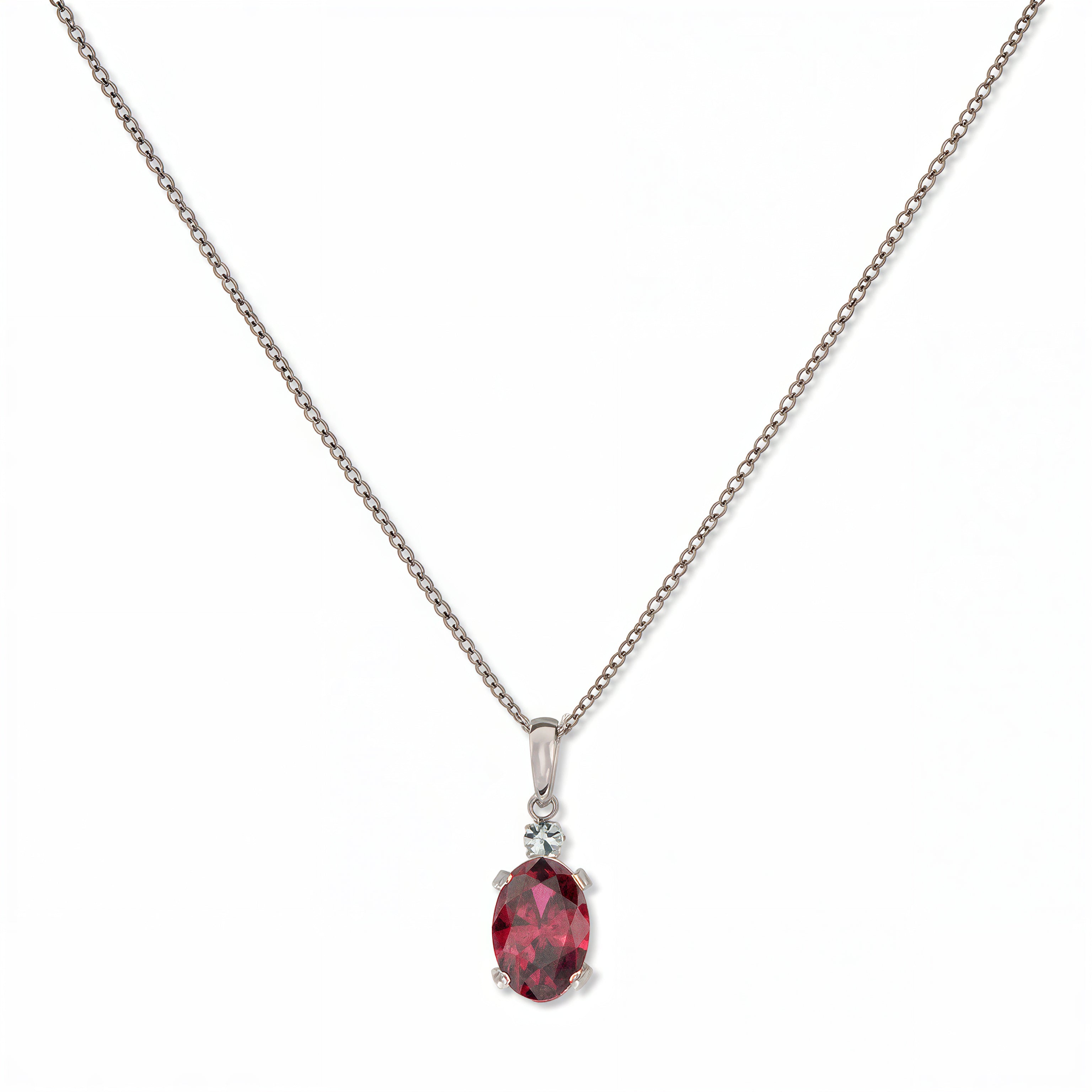 A Skōsh Kids July Birthstone Oval Ruby Cubic Zirconia Necklace by Skōsh Jewelry, featuring an oval faceted red stone in a prong setting on a fine sterling silver chain, displayed against a white background.