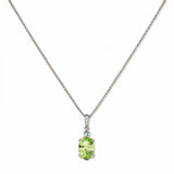 A Skōsh Kids August Birthstone Oval Peridot Cubic Zirconia Necklace by Skōsh Jewelry, featuring an oval faceted light green stone in a prong setting on a fine sterling silver chain, displayed against a white background.