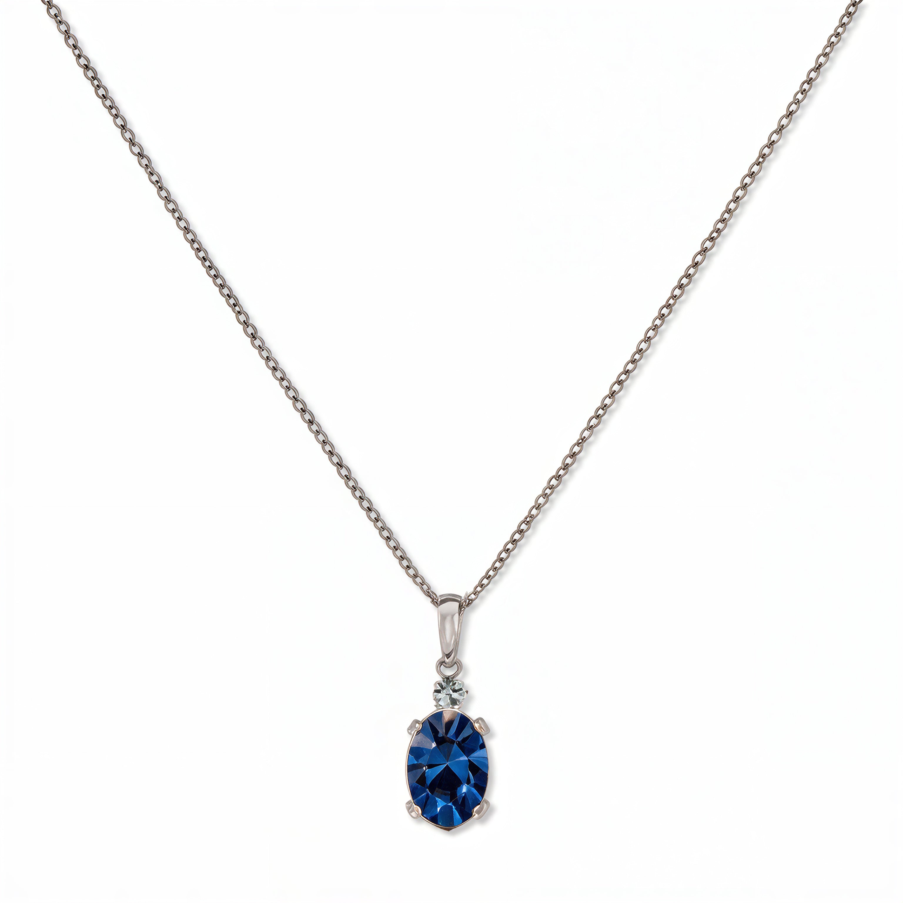 A Skōsh Kids September Birthstone Oval Sapphire Cubic Zirconia Necklace by Skōsh Jewelry, featuring an oval faceted deep blue stone in a prong setting on a fine sterling silver chain, displayed against a white background.