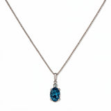 A Skōsh Kids December Birthstone Oval Aqua Cubic Zirconia Necklace by Skōsh Jewelry, featuring an oval faceted blue stone in a prong setting on a fine sterling silver chain, displayed against a white background.
